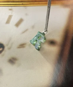 Carved moss agate letter R pendant on a silver-colored chain