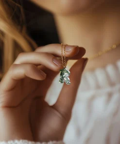 Moss agate initial necklace shown held near the neckline