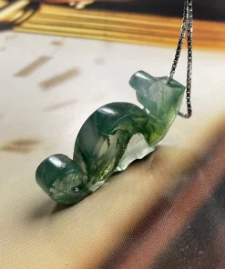 Angled view of carved moss agate seahorse pendant