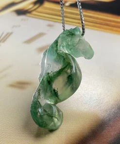 Hand-carved moss agate seahorse pendant showing curled tail and green mineral patterns