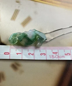 Carved moss agate seahorse pendant beside centimeter tape markings