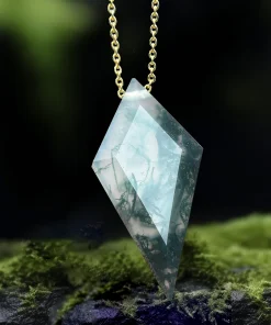 Faceted kite moss agate pendant with gold-colored chain displayed among green moss