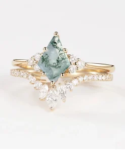 Angled view of pear moss agate ring set with curved accent-set wedding band