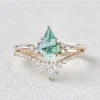 Pear moss agate engagement ring with clear accent stones and a curved matching band