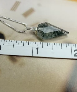 Prismatic moss agate pendant beside ruler markings