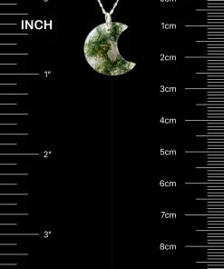 Crescent moon moss agate pendant beside inch and centimeter scale markings