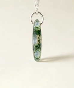 Side view of moss agate crescent moon pendant showing polished thickness and pendant ring