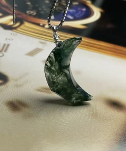 Angled view of crescent moon moss agate pendant with green inclusions