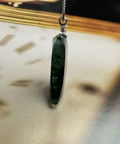 Edge view of faceted moss agate crescent moon pendant