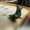 Faceted crescent moon moss agate pendant displayed on a clock-face background
