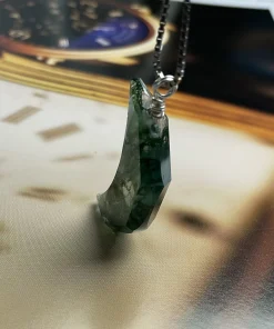 Side view of faceted moss agate moon pendant showing its thickness