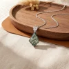 Kite moss agate pendant with silver flower motif displayed beside a wooden tray