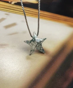 Angled view of carved moss agate star pendant