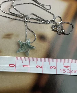 Moss agate star pendant beside centimeter tape markings