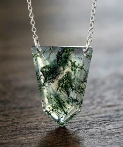 Angled view of faceted shield moss agate pendant and silver-colored chain