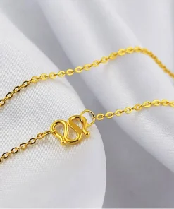 Gold-colored chain and clasp displayed on white fabric