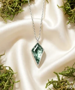 Kite moss agate necklace displayed on ivory fabric among green moss