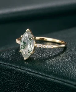 Angled view of marquise moss agate ring on a dark green display surface
