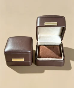 Open and closed brown jewelry boxes with an empty padded ring insert
