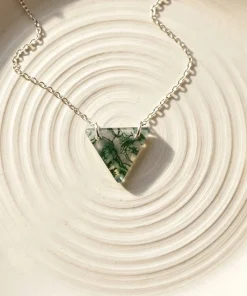 Natural triangle moss agate pendant displayed on a ridged ivory dish