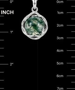 Organic vine-frame moss agate pendant beside inch and centimeter scale markings