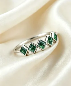 Five square moss agate gemstones arranged across a silver-colored band on ivory fabric