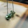 Three round moss agate discs suspended from a silver-colored box chain