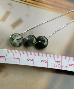 Round moss agate disc necklace beside centimeter tape markings