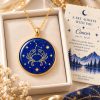 Cancer zodiac necklace featuring a polished natural lapis lazuli pendant with gold Cancer constellation design, displayed in an ivory jewelry box with a matching zodiac gift card