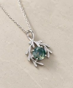 Angled view of rounded moss agate pendant with flowing botanical leaves