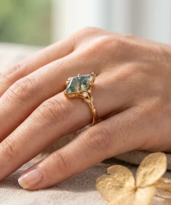 Yellow gold kite moss agate leaf ring shown on a hand